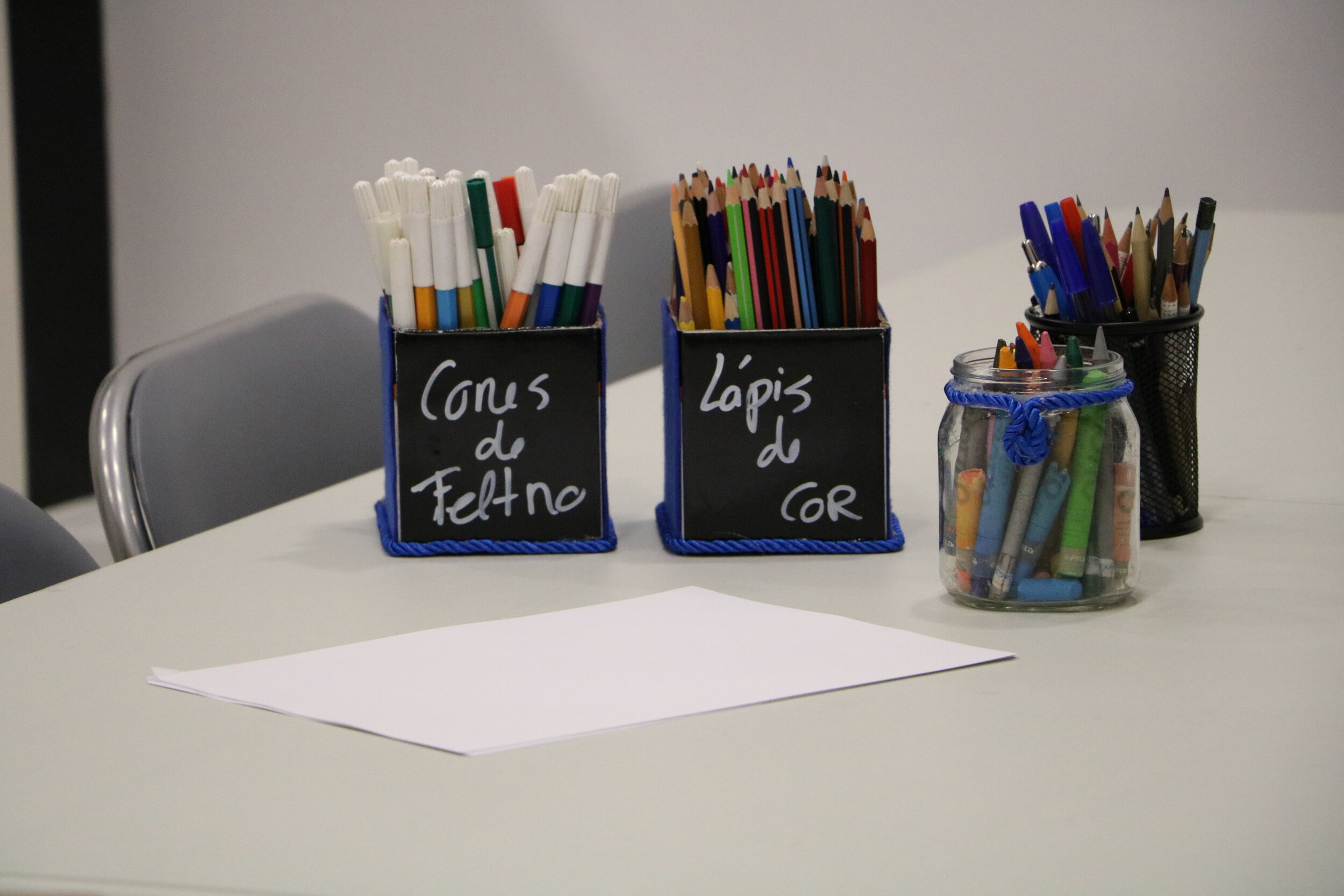 Canetas de feltro, lápis de cor e material de escrita sobre uma mesa